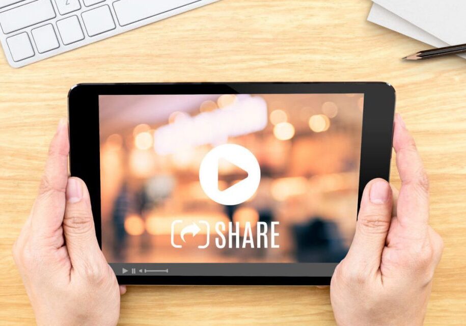 Hand holding tablet with Video sharing on screen on wood table ,Internet marketing concept